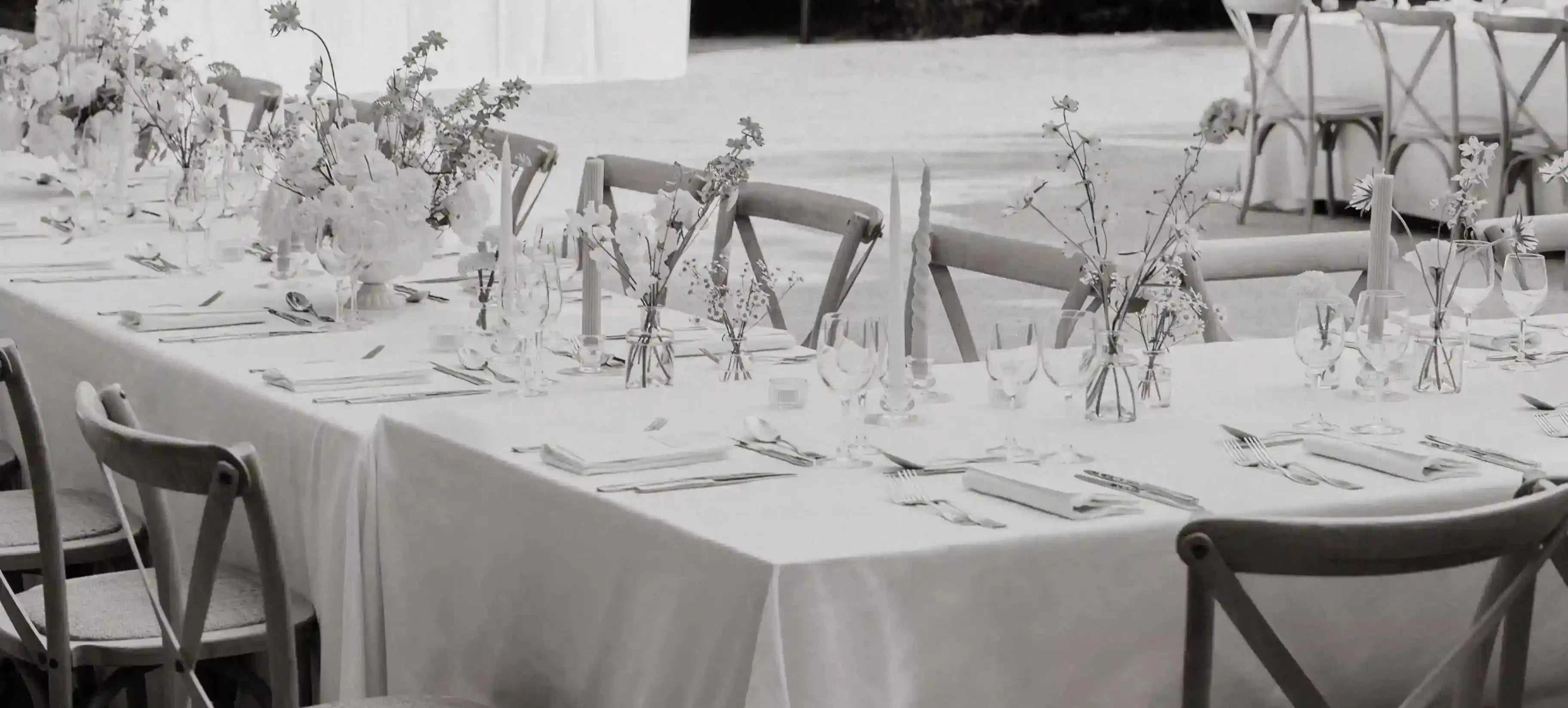 Wedding dinner tablescape with Lavender Muse wedding menus, flower arrangements spaced throughout the table, outside wedding dinner