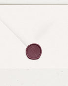 Burgundy wax seal on white wedding envelope with flower embossing