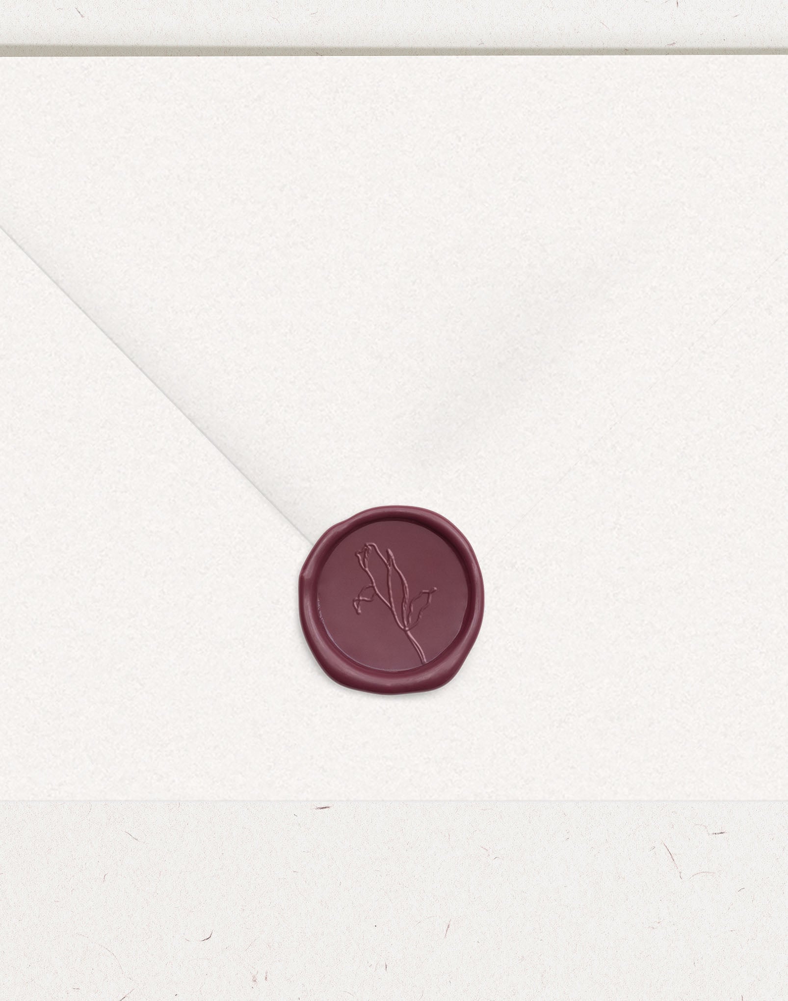 Burgundy wax seal on white wedding envelope with flower embossing