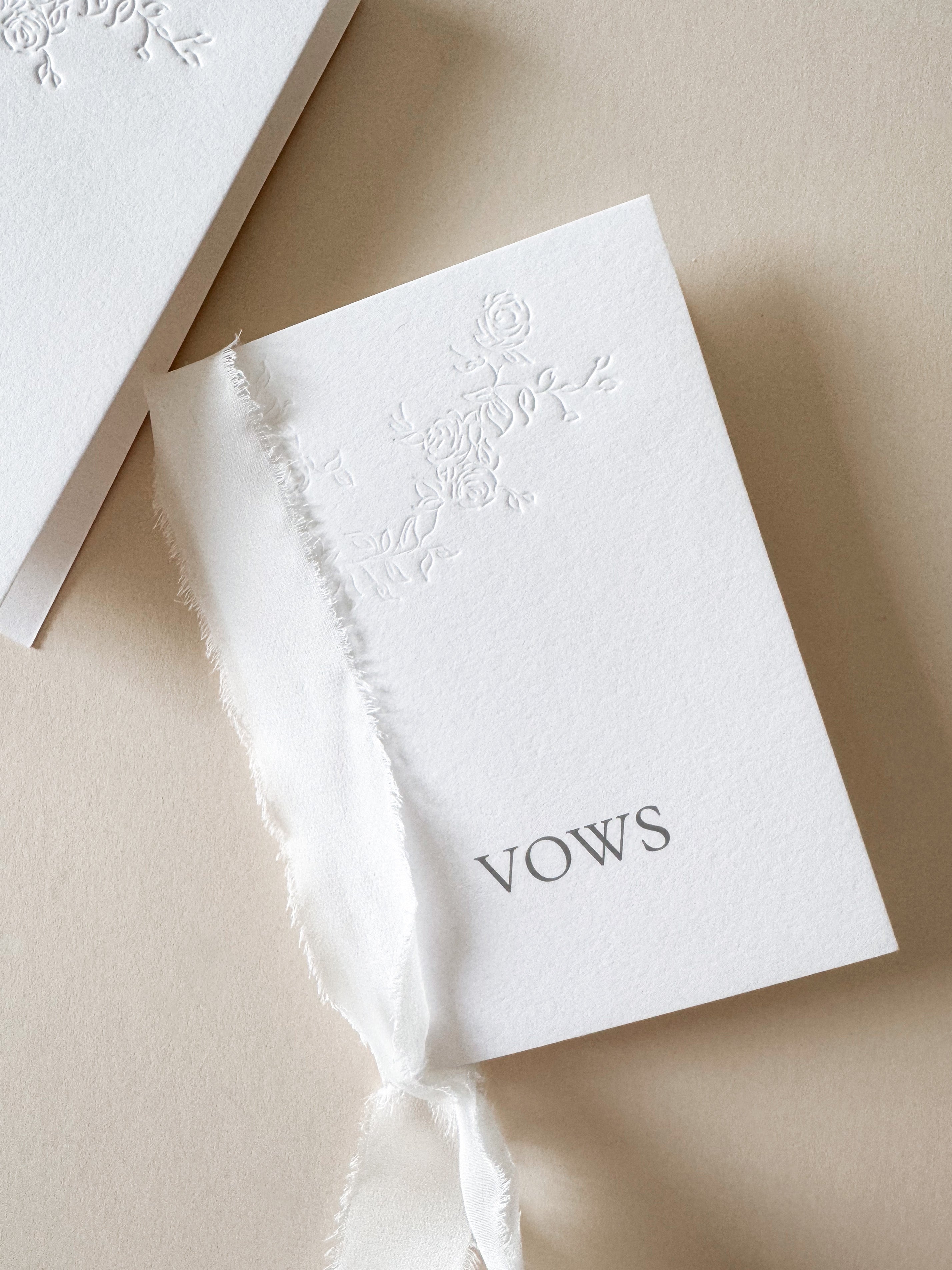 White wedding vows book with floral letterpress design bound with silk ribbon. Personalised with digitally printed names.