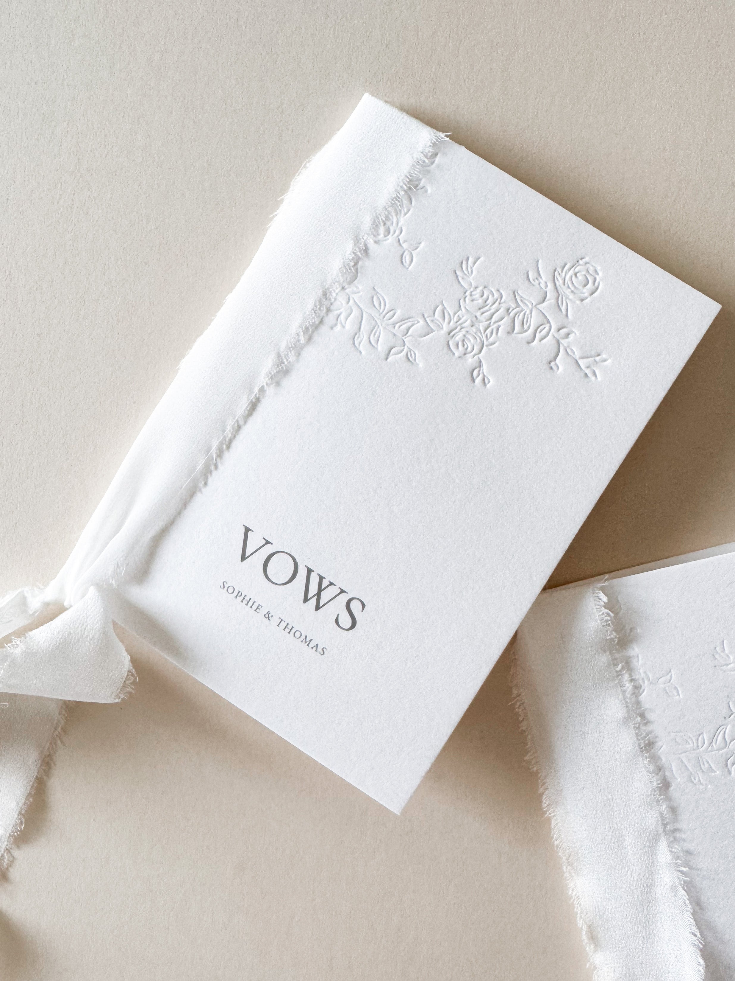 White wedding vows book with floral letterpress design bound with silk ribbon. Personalised with digitally printed names.