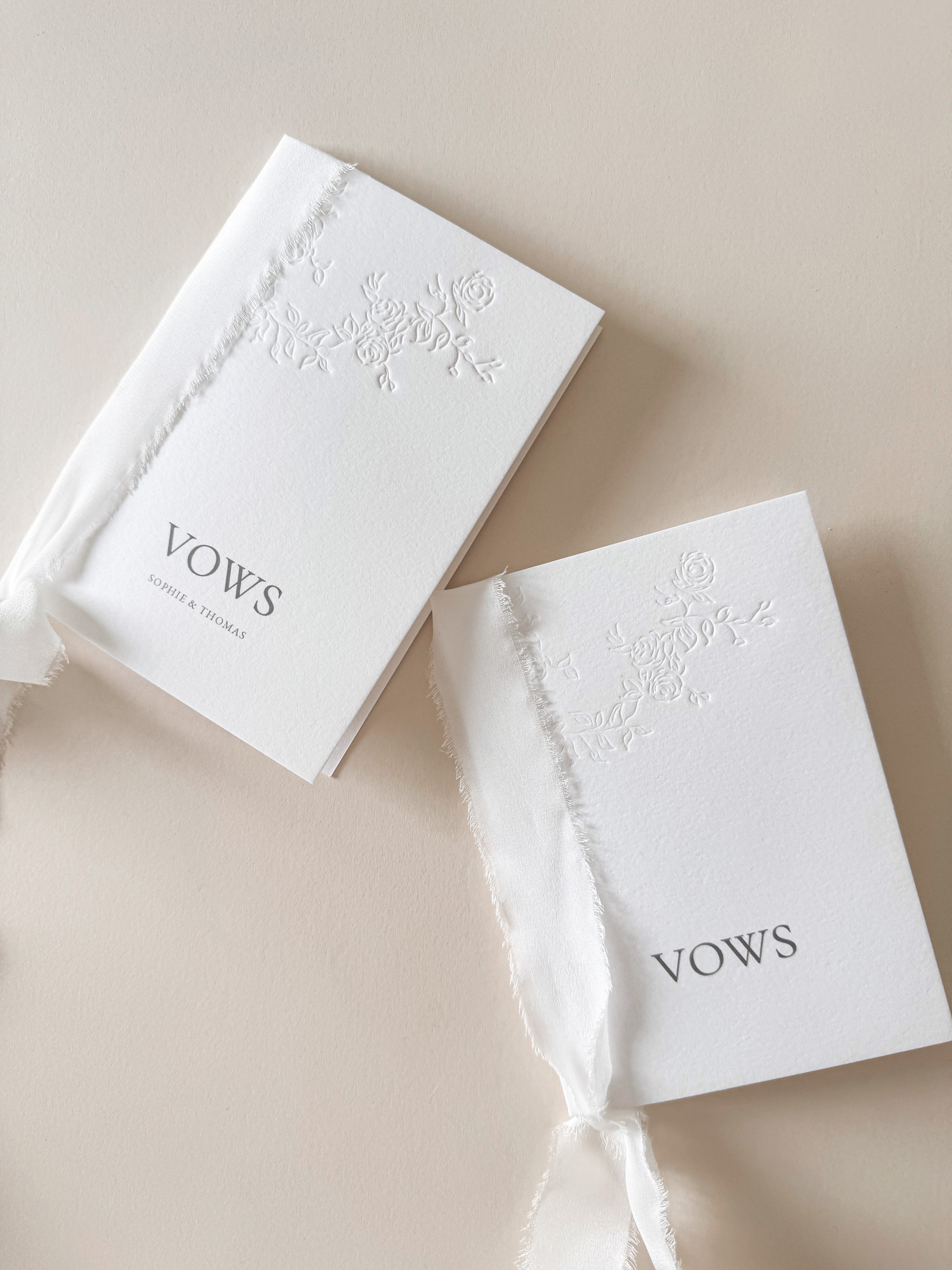 Two white wedding vows book with floral letterpress design bound with silk ribbon. Personalised with digitally printed names.
