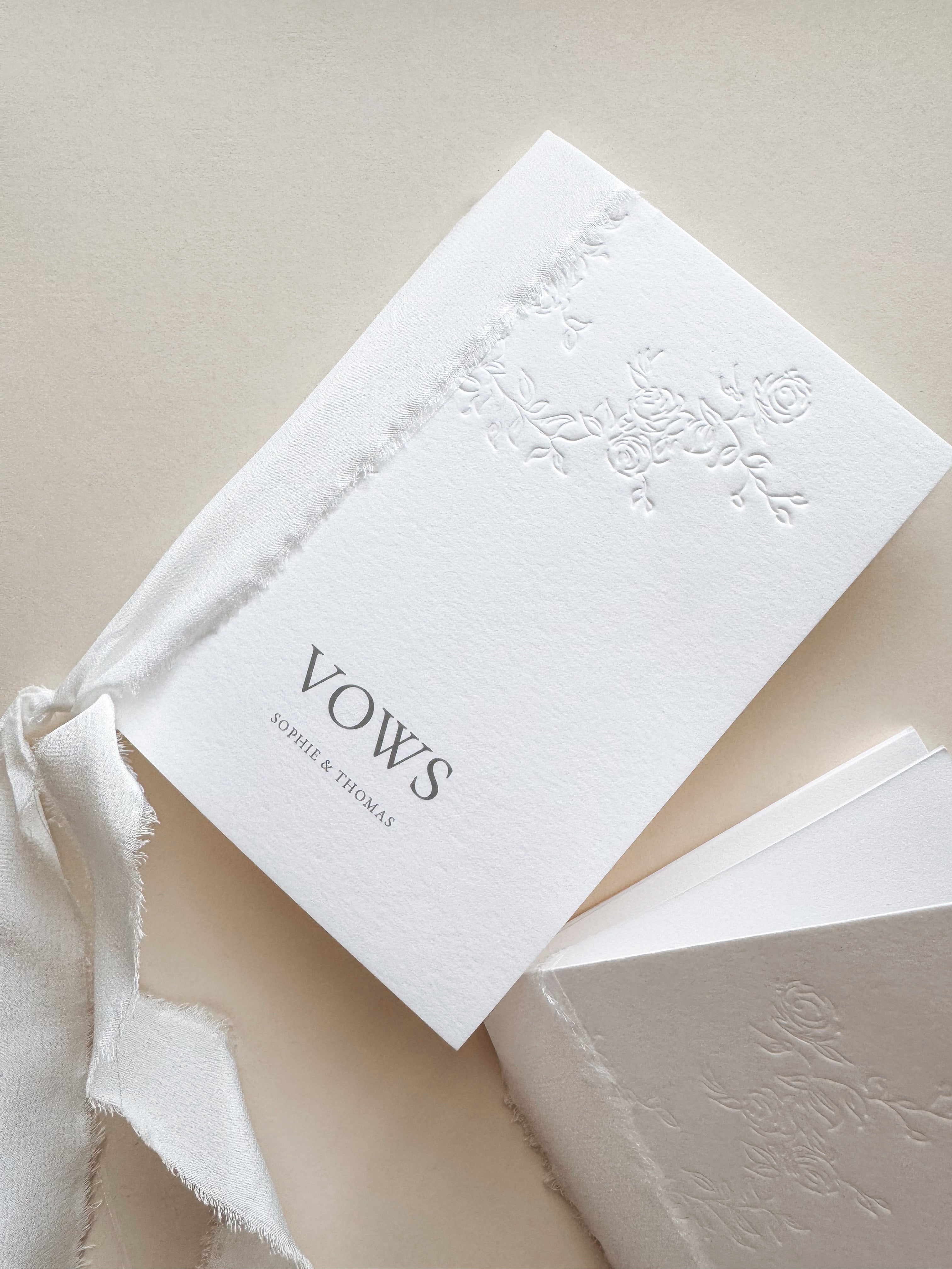 White wedding vows book with floral letterpress design bound with silk ribbon. Personalised with names.