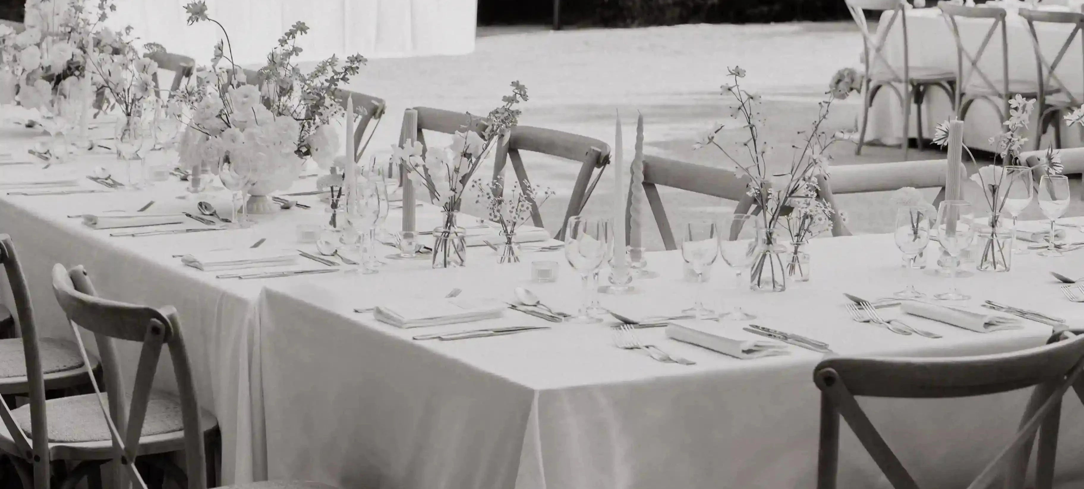 Wedding dinner tablescape with Lavender Muse wedding menus, flower arrangements spaced throughout the table, outside wedding dinner