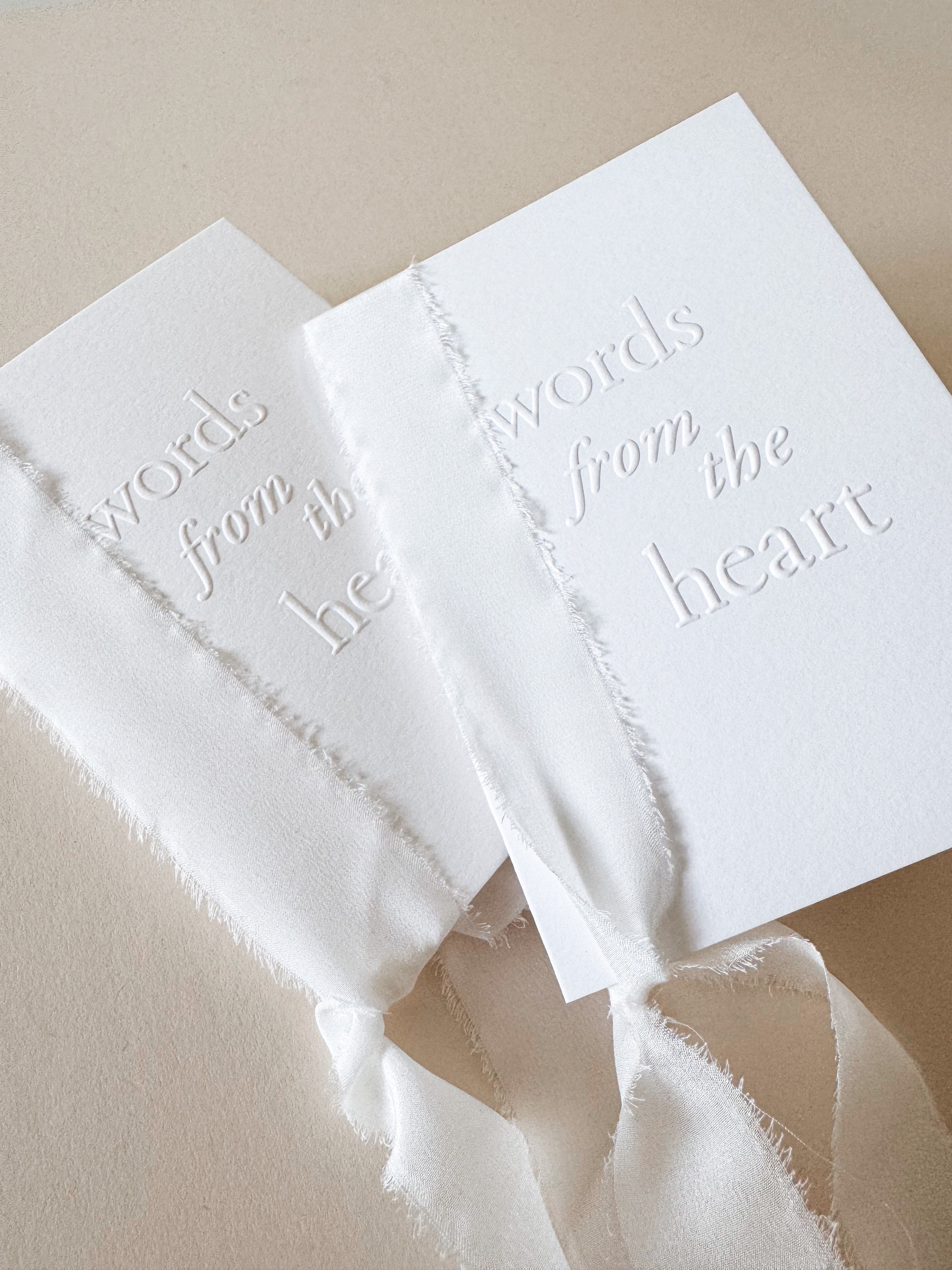 Two handmade booklets made from white cotton card, bound with white silk ribbon with the words 'words from the heart' embossed on the front cover. Perfect for wedding speeches, ceremony readings or love letters.