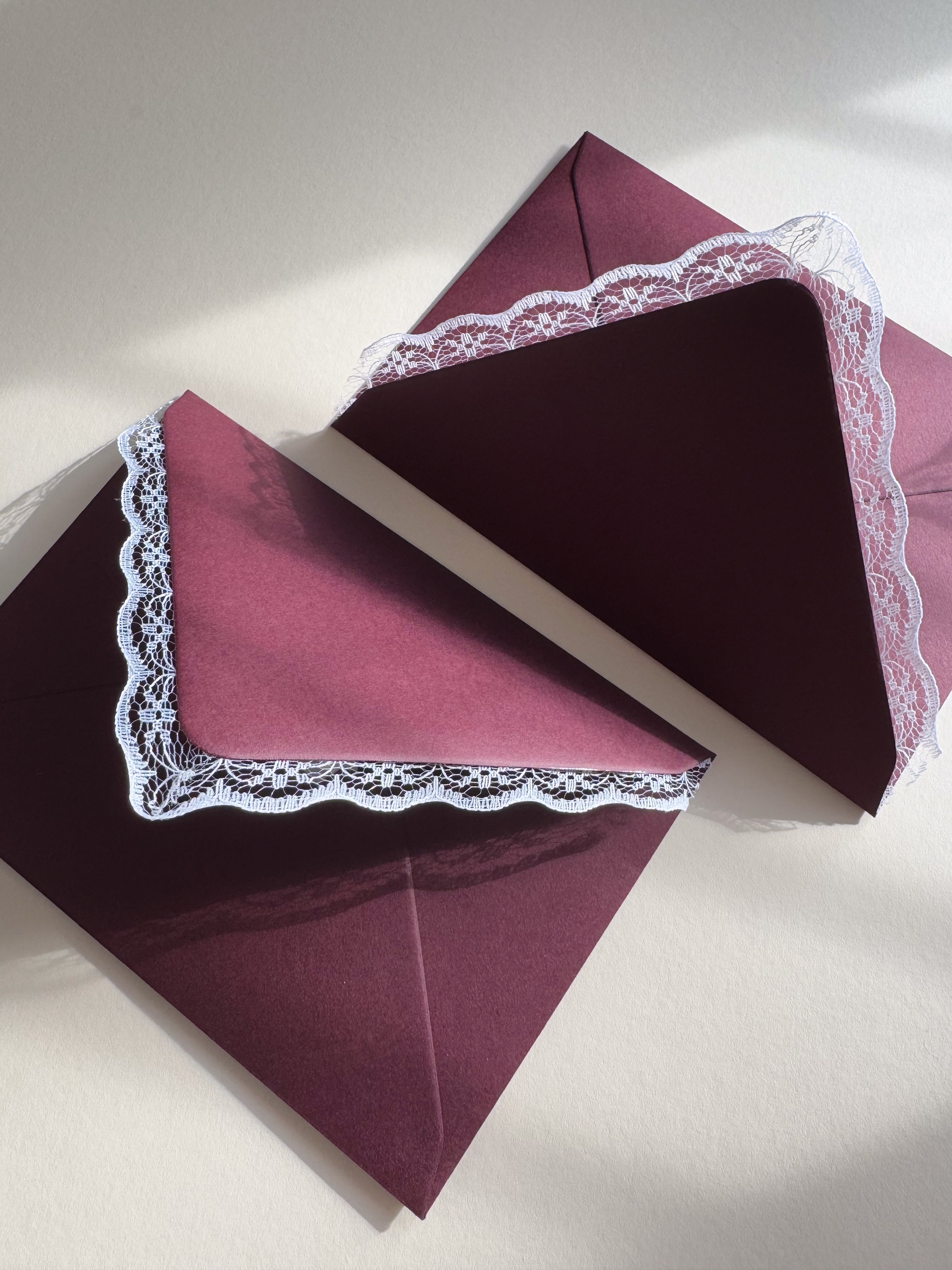 Two burgundy envelopes with white lace trim
