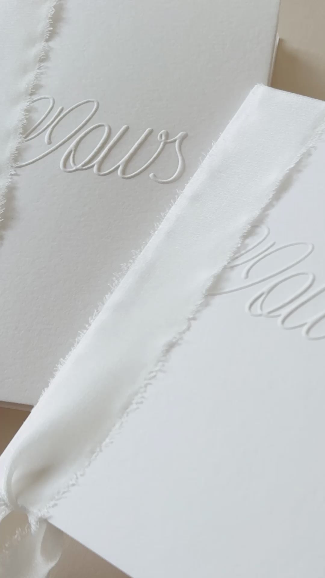 Video showing wedding Vow booklets, handmade in white card with the word 'Vows' embossed on the front, bound together with white silk ribbon. For ceremony use, vows and anniversary gifts.