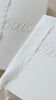 Video showing wedding Vow booklets, handmade in white card with the word 'Vows' embossed on the front, bound together with white silk ribbon. For ceremony use, vows and anniversary gifts.
