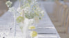 Dreamy outside wedding dinner tablescape showing floral arrangements in whites blues and yellows and lavender muse wedding menus